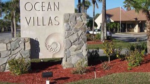A sign for Ocean Villas with a stone wall and a logo. - Highly rated Condo in Ocean Front Community, Wheelchair accessible, Dog friendly (St Augustine Beach)