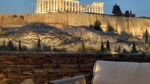 Vista del Partenón en Atenas, con un muro de piedra y un sofá al frente.