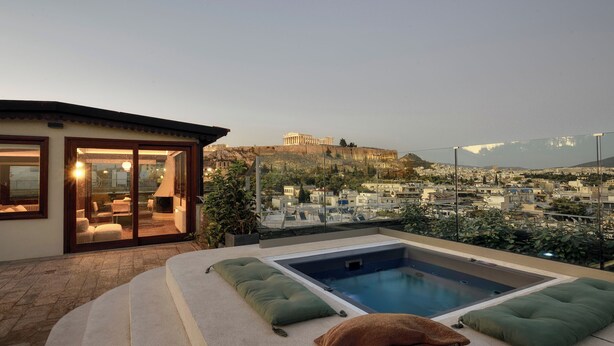 Zona de piscina en la azotea con vistas a un edificio histórico al fondo.