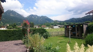 Ländliche Umgebung mit Garten, Holzbau und Häusern im Hintergrund.