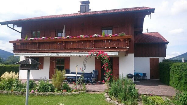 Ein zweistöckiges Holzhaus mit Balkon, Veranda und Garten.
