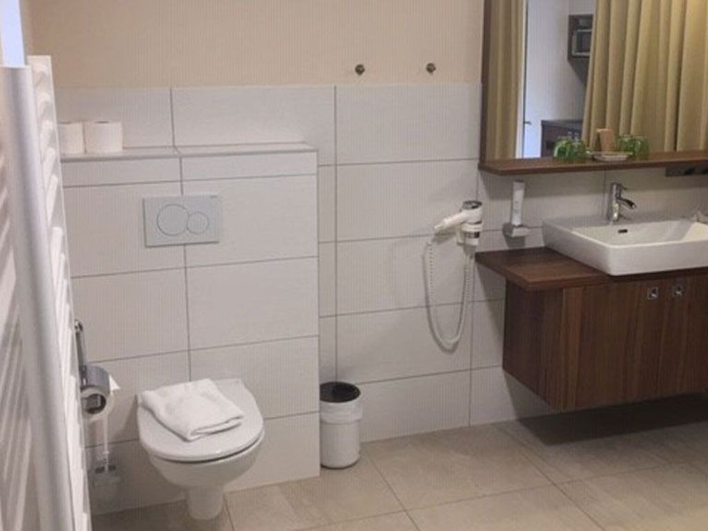 A bathroom with a toilet, a sink, a mirror, and a shower.