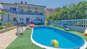 A swimming pool with a blue inflatable ball, surrounded by a white fence and a green lawn. - Amazing apartment in Zadar with WiFi (Zadar)