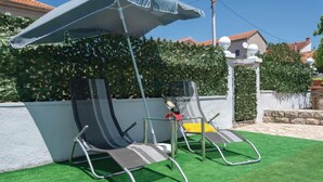 Two lounge chairs with a canopy, positioned on artificial grass, with a hedge and a building in the background. - Amazing apartment in Zadar with WiFi (Zadar)