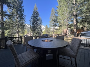 Relax by the fire pit in this serene outdoor space surrounded by tall pine trees.