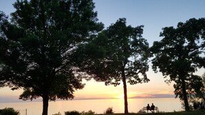 Une vue sur le coucher de soleil, avec un banc et des arbres au premier plan.