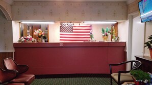 Un comptoir d’accueil orné d’un drapeau américain, d’un panneau « interdiction de fumer » et d’un écran de télévision.