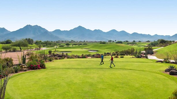 Um campo de golfe com vista clara para as montanhas ao fundo.