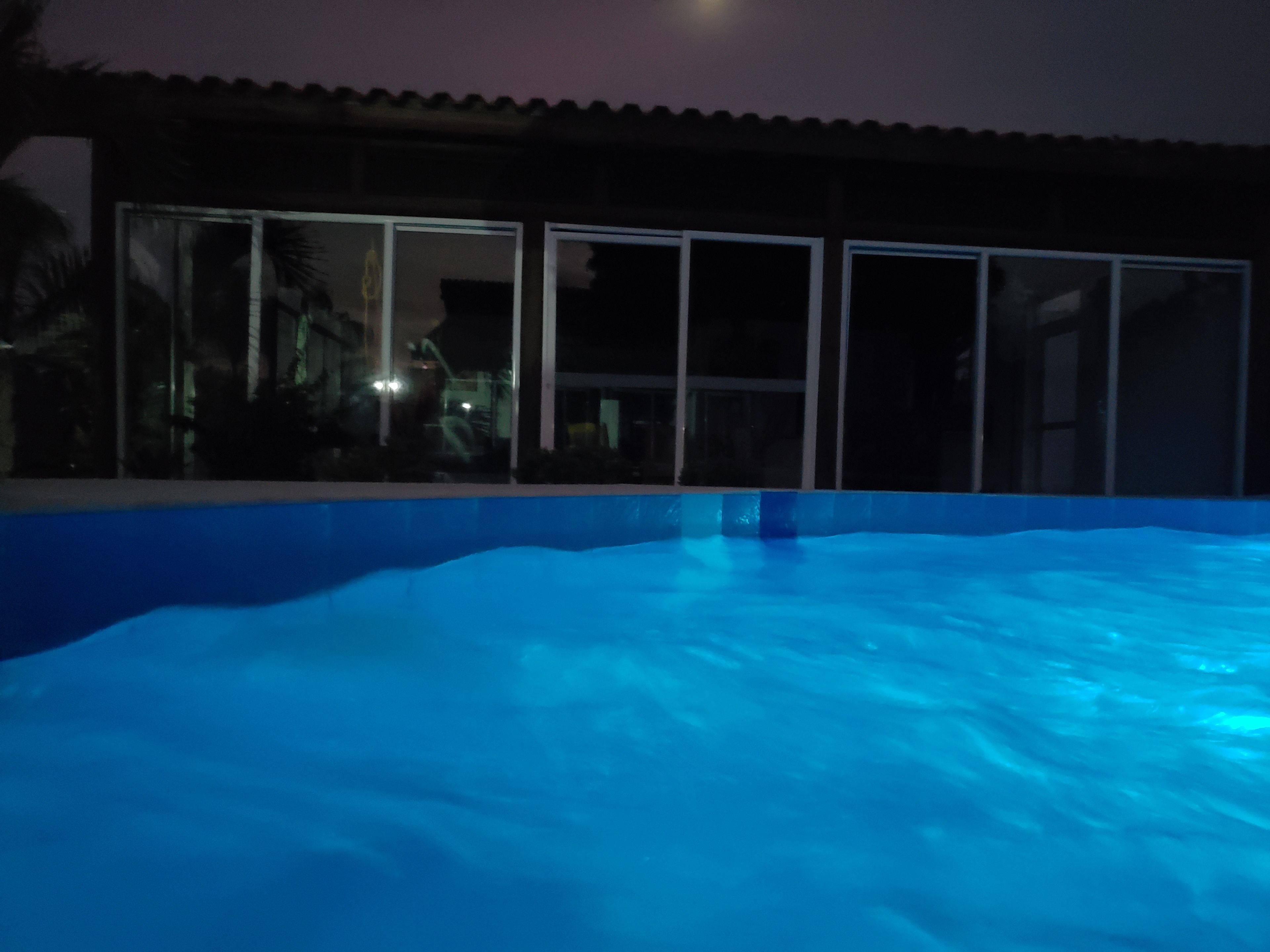Una piscina con borde azul, rodeada por un edificio con grandes ventanales.