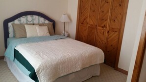 Un dormitorio con cama, lámpara de noche y armario de madera.