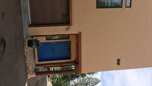 Un edificio con una puerta marrón y una azul, una ventana y una planta en maceta.