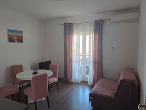 Una stanza con un tavolo rotondo, quattro sedie, un letto e una finestra con tende.