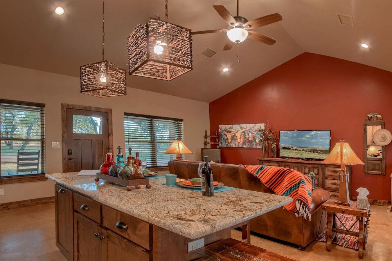 A spacious living area with a large island, a ceiling fan, and a television.