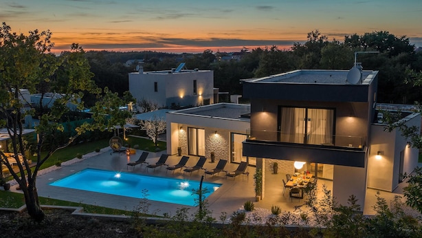 Ein modernes Haus mit Schwimmbad, Sitzgelegenheiten im Freien und einer gut beleuchteten Terrasse.