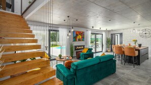 Ein modernes Wohnzimmer mit Treppe, Kamin und Essbereich mit Blick ins Freie.