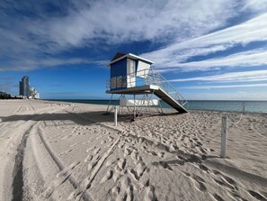 A lifeguard tower on a sandy beach with a clear sky.