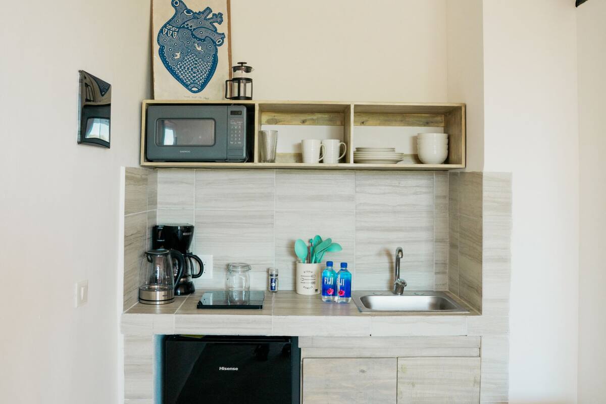 Una cocina compacta equipada con microondas, cafetera, lavabo y lavavajillas.