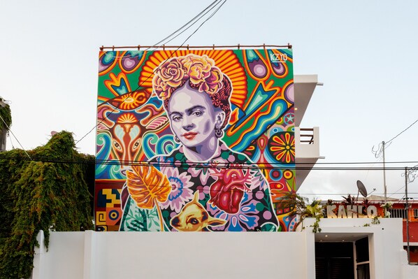 A colorful mural on a building facade with a geometric pattern and a large flower design. - Great Villas Studios & Residences - The Kahlo (Playa del Carmen)