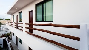 A modern building with a white facade, large windows, and a wooden balcony railing. - Great Villas Studios & Residences - The Kahlo (Playa del Carmen)