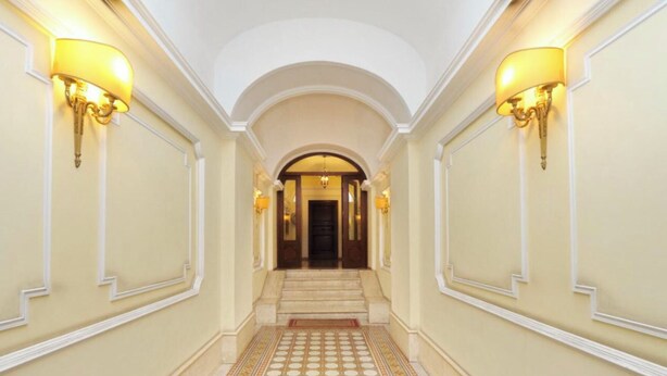 A grand hallway with a tiled floor, a central staircase, and wall-mounted lighting. - VENETO COMFORTABLE APARTMENT (one night for up to 6 people) (Roma)