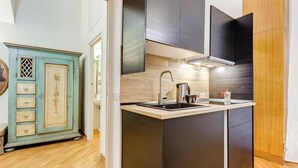 A modern kitchen with a central island, dark cabinetry, and a vintage-style cabinet in the background. - VENETO COMFORTABLE APARTMENT (one night for up to 6 people) (Roma)
