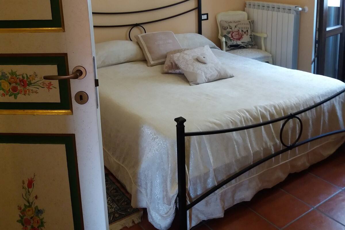 Une chambre à coucher avec un lit, un radiateur, une porte ornée de motifs floraux et un luminaire suspendu.