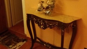 A room with a wooden console table, a mirror, and a plastic bag on the table. - Myosotis (Introdacqua)