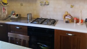 A kitchen with wooden cabinets, a gas stove, and a dishwasher. - Myosotis (Introdacqua)