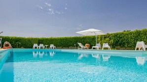 A clear blue pool with white lounge chairs and umbrellas, surrounded by a hedge. - Aurelia by Interhome (Castelfiorentino)
