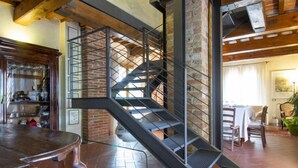 A spiral staircase with metal railings in a rustic interior with exposed brick walls and wooden beams. - Aurelia by Interhome (Castelfiorentino)