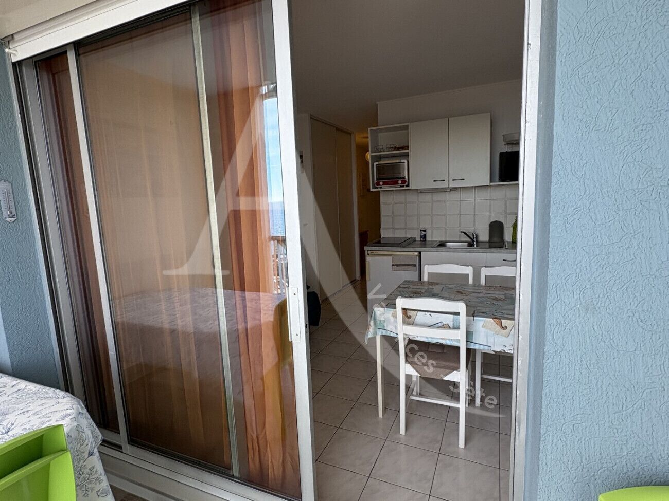 A balcony with a sliding glass door leading to a kitchen area.