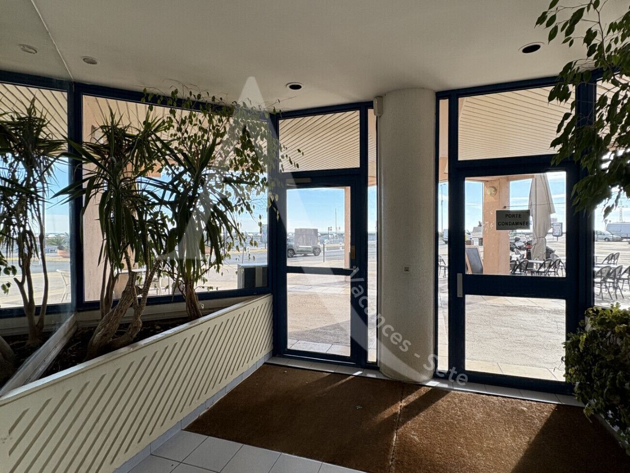 A modern interior with large windows, a radiator, and potted plants.