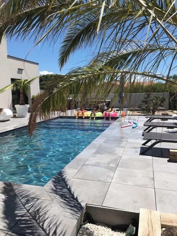 Relax by the clear pool surrounded by a deck and lounge chairs.