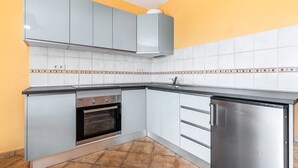 Una cucina compatta con mobili grigi, forno integrato e frigorifero in acciaio inossidabile.
