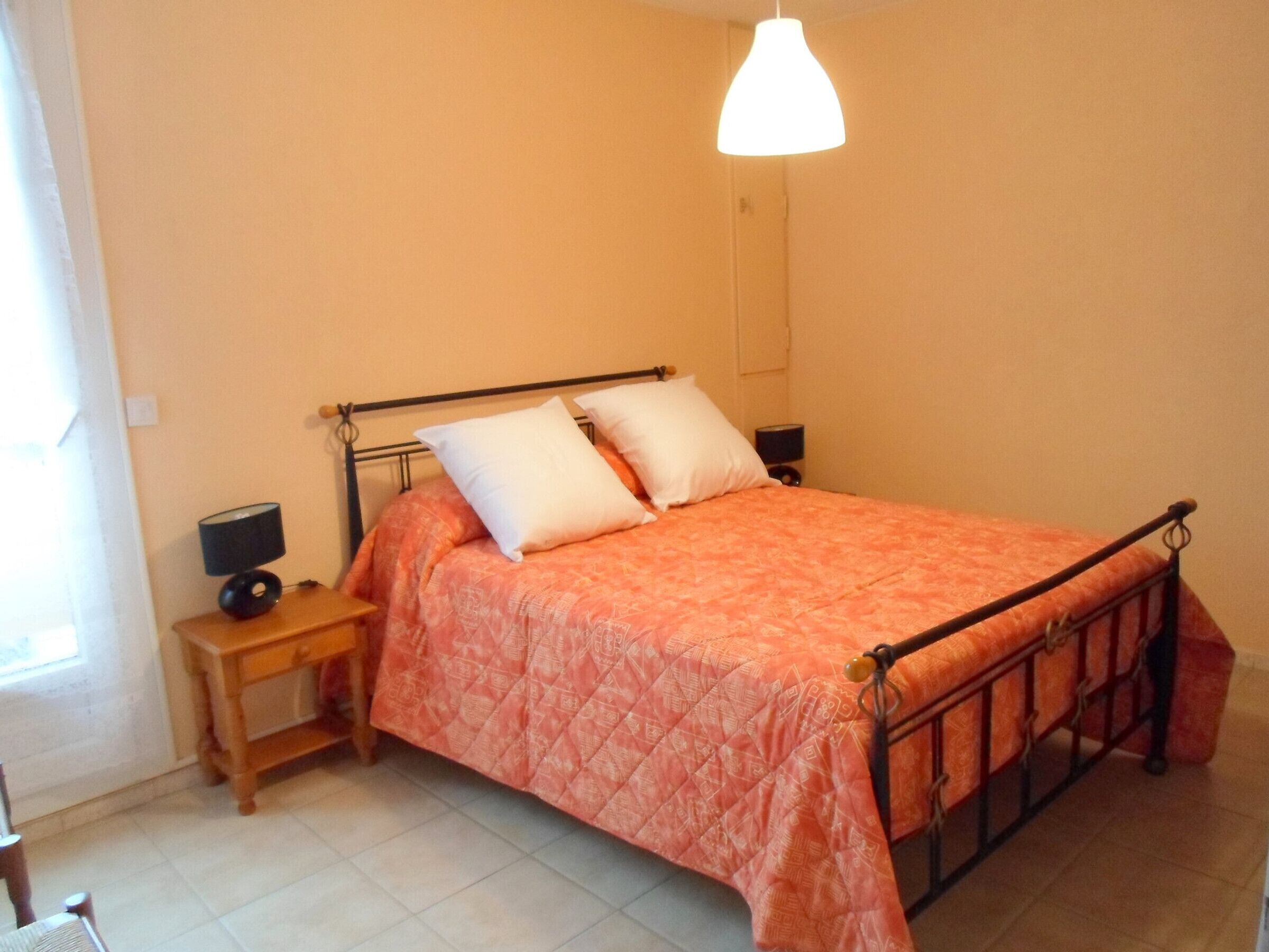 Un dormitorio con cama, mesitas de noche y una lámpara colgante.