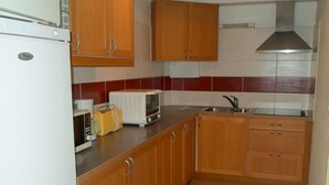 A compact kitchen with wooden cabinets, a white refrigerator, a microwave, and a toaster. - 45m² Apartment in Balaruc-les-Bains, pets allowed (Balaruc-les-Bains)