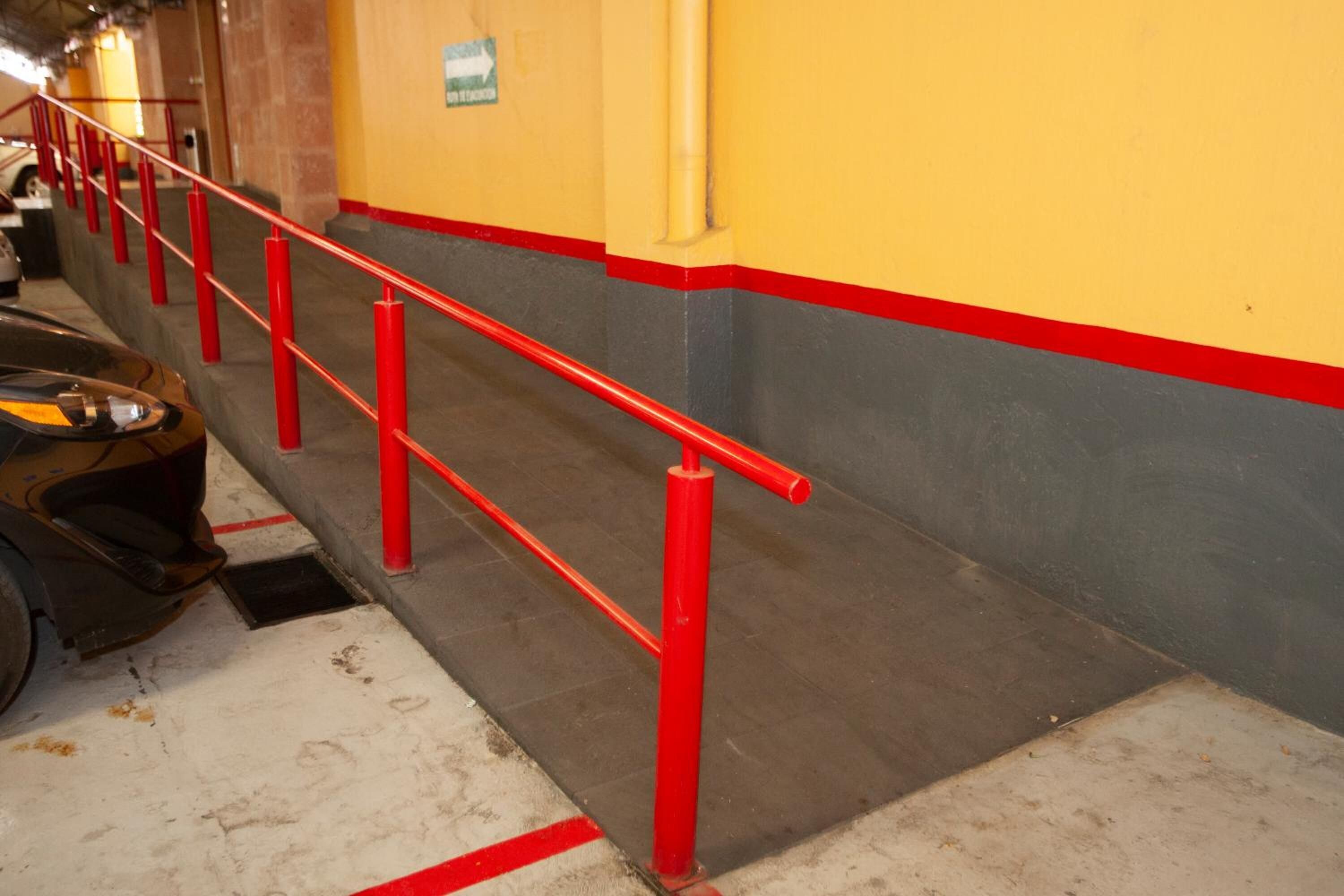 A parking garage with red railings and a yellow wall.