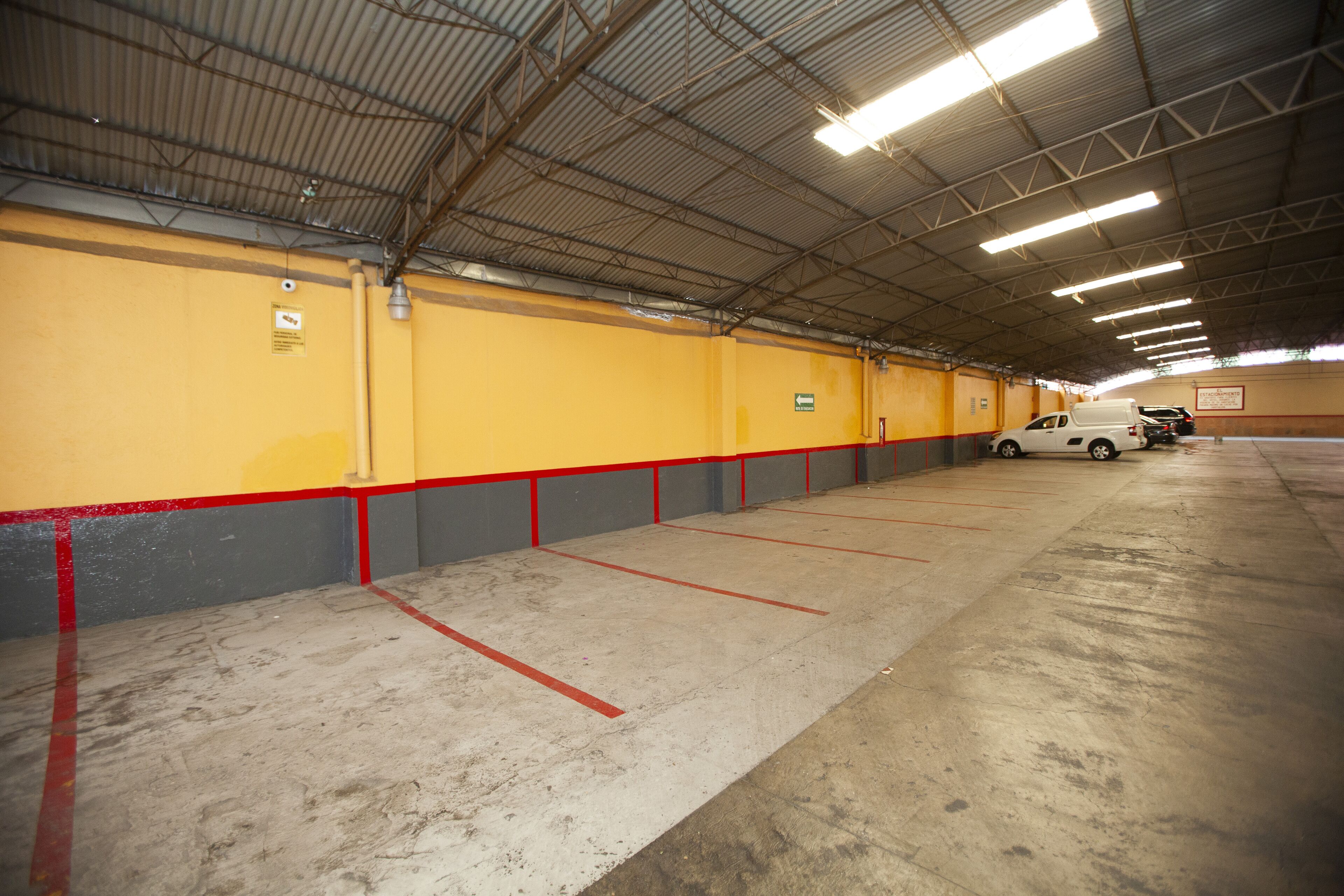 A large indoor parking garage with yellow walls and red accents.