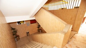 Una scala rivestita di piastrelle color beige, con ringhiera in metallo e piante in vaso.