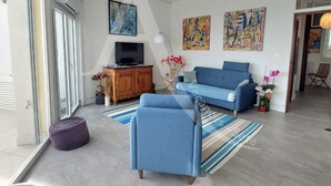 A modern living room with a sofa, a television, and artwork on the walls. - APPARTEMENT 3 CHAMBRES, GARAGE, LARGE TERRASSE VUE UNIQUE (Sète)