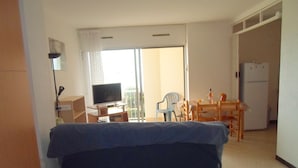 Habitación de hotel con cama, televisión, escritorio con silla y zona de comedor con mesa y sillas.