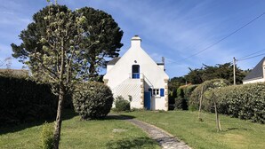 A white building with a blue door and window, surrounded by greenery and a stone pathway. - "Secrets of Petit Rohu" - 2ch, garden & beach (Saint-Pierre-Quiberon)