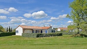 A white building with a red roof, surrounded by green grass and hedges. - Villa in France with Pool and Private Garden (Vasles)