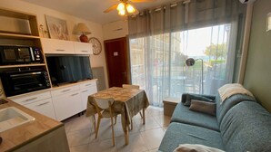 A compact living space with a kitchenette, a dining area, and a seating area with a sofa and a table.