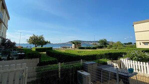 A residential area with a view of the sea, a fenced garden, and a building with a flat roof.