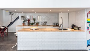 Une cuisine moderne avec des carreaux de métro blancs, un plan de travail en bois et un grand îlot central doté d’un évier.