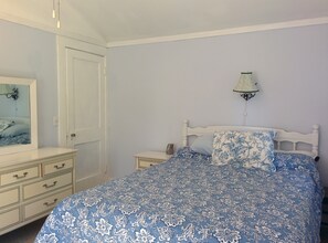 A bedroom with a bed, a dresser, a nightstand, a lamp, and a mirror.