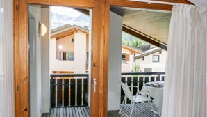 Un balcon en bois offrant une vue sur les maisons voisines, avec une table et des chaises.