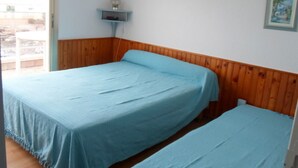 Ett rum med två sängar, träpanel på väggarna, en liten hylla med en lampa och en inramad tavla på väggen.