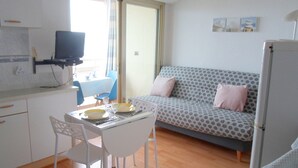 Ett kompakt bostadsutrymme med ett litet kök, en matplats och en soffa.